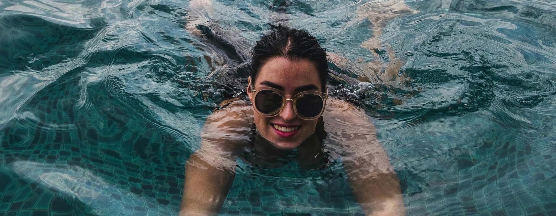 woman with sunglasses swims in pool